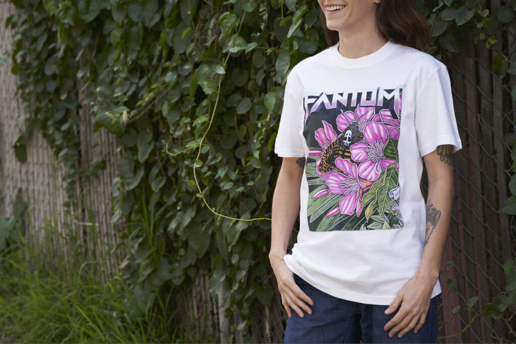 kayla wearing moth print t-shirt standing in front of green ivy and fence