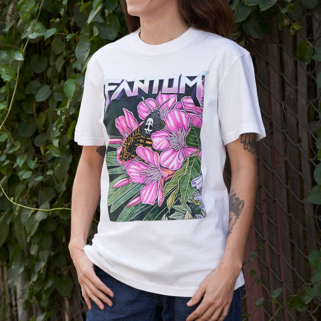 kayla wearing moth print t-shirt standing in front of green ivy and fence