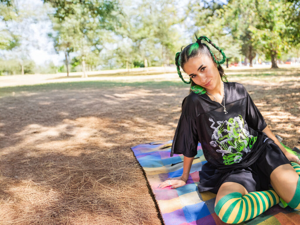 rib wearing frog printed jersey sitting on picnic blanket with frog on shoulder